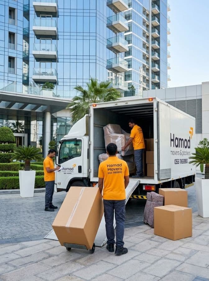 Hamad Movers team loading furniture into moving truck outside a modern high-rise residential building in Dubai - Hamad Movers Dubai